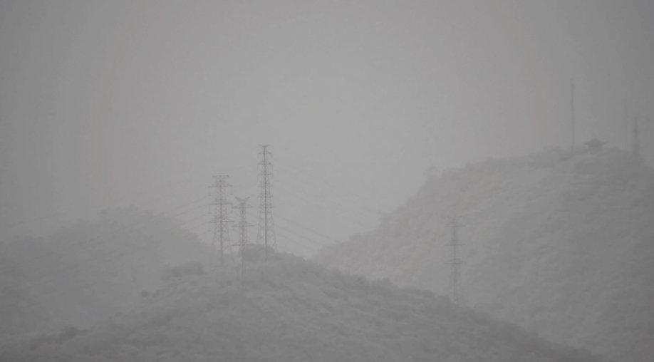 [photo] Blurry image of grey, snowy hill landscape with decreased visibility compared to enhanced and clear image of snowy hills