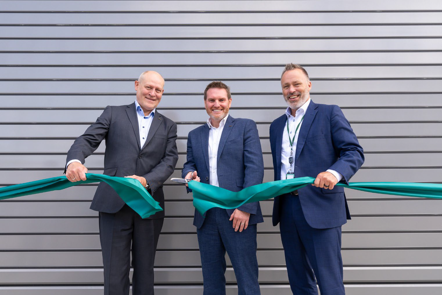 A group of men in suits holding a green ribbon